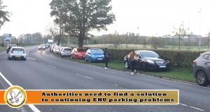 Image of cars parked on verges and pedestrians walking near traffic. Very dangerous.