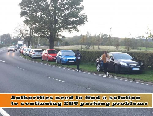 Image of cars parked on verges and pedestrians walking near traffic. Very dangerous.